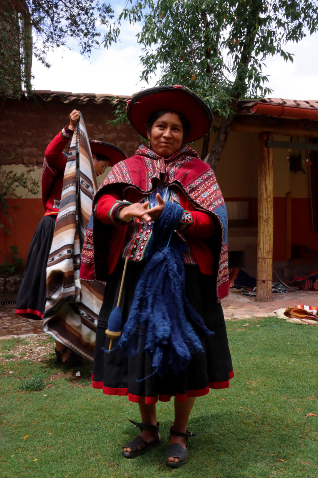 A Peruvian woman smiling while showing off her weaving technique at El Centro De Textiles Tradicionales Del Cusco in Chinchero, Peru