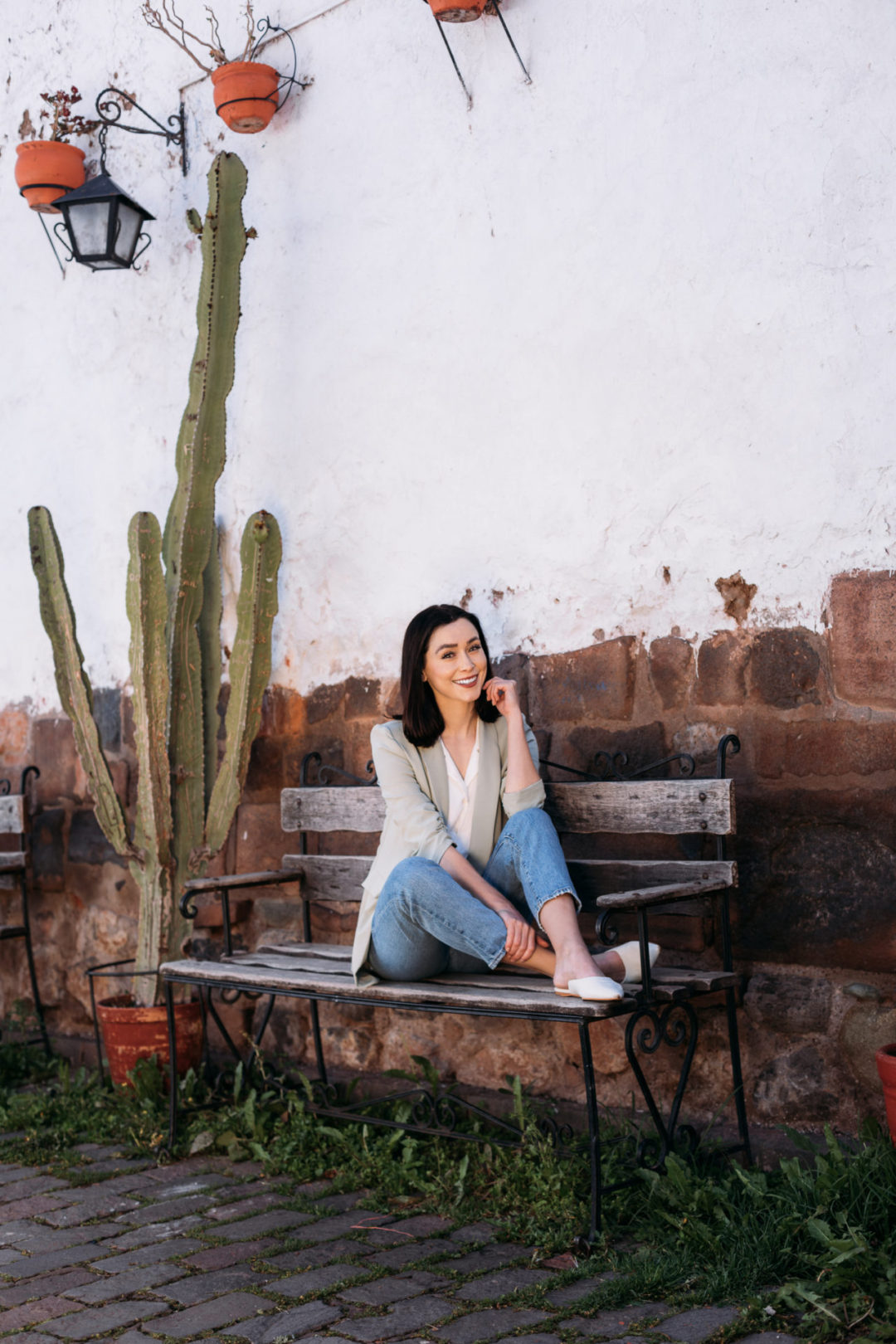 Travel Blogger Jordan Gassner smiling and sitting with her feet up on the bench at Calle Tocuyeros in Cusco, Peru