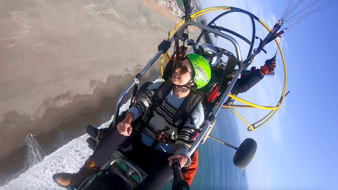 Travel Blogger Jordan Gassner smiling and looking left while paragliding over the Peruvian coastline on Christmas Eve 2021