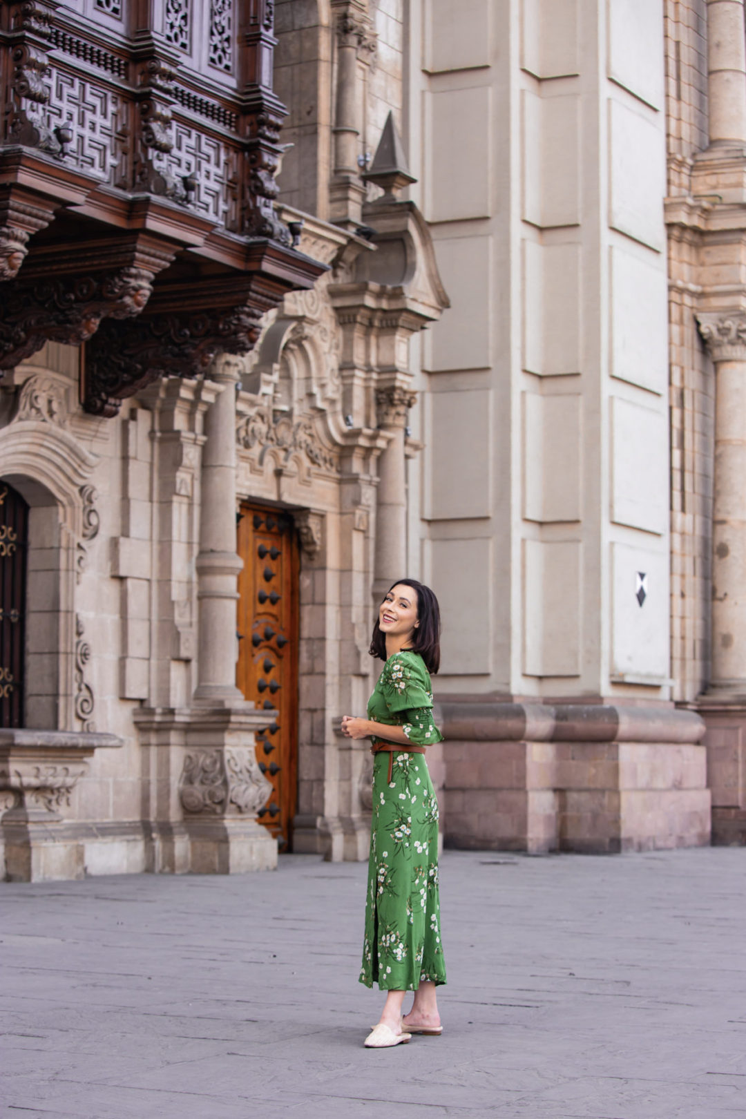 Travel Blogger Jordan Gassner throwing her head back and smiling in front of Lima's Parroquia El Sagrario, decorated for the Christmas Season