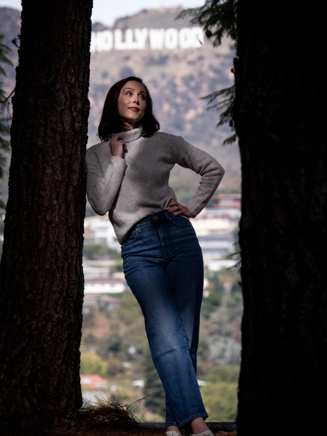 Travel Blogger Jordan Gassner leaning against a tree while looking up and smiling at Barnsdall Art Park to get unique Hollywood Sign photos