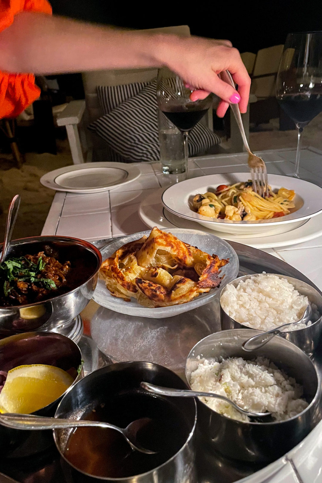 Travel Blogger Jordan Gassner twirling the seafood pasta with a fork near a mezze platter at Tillie's on Grand Cayman Island