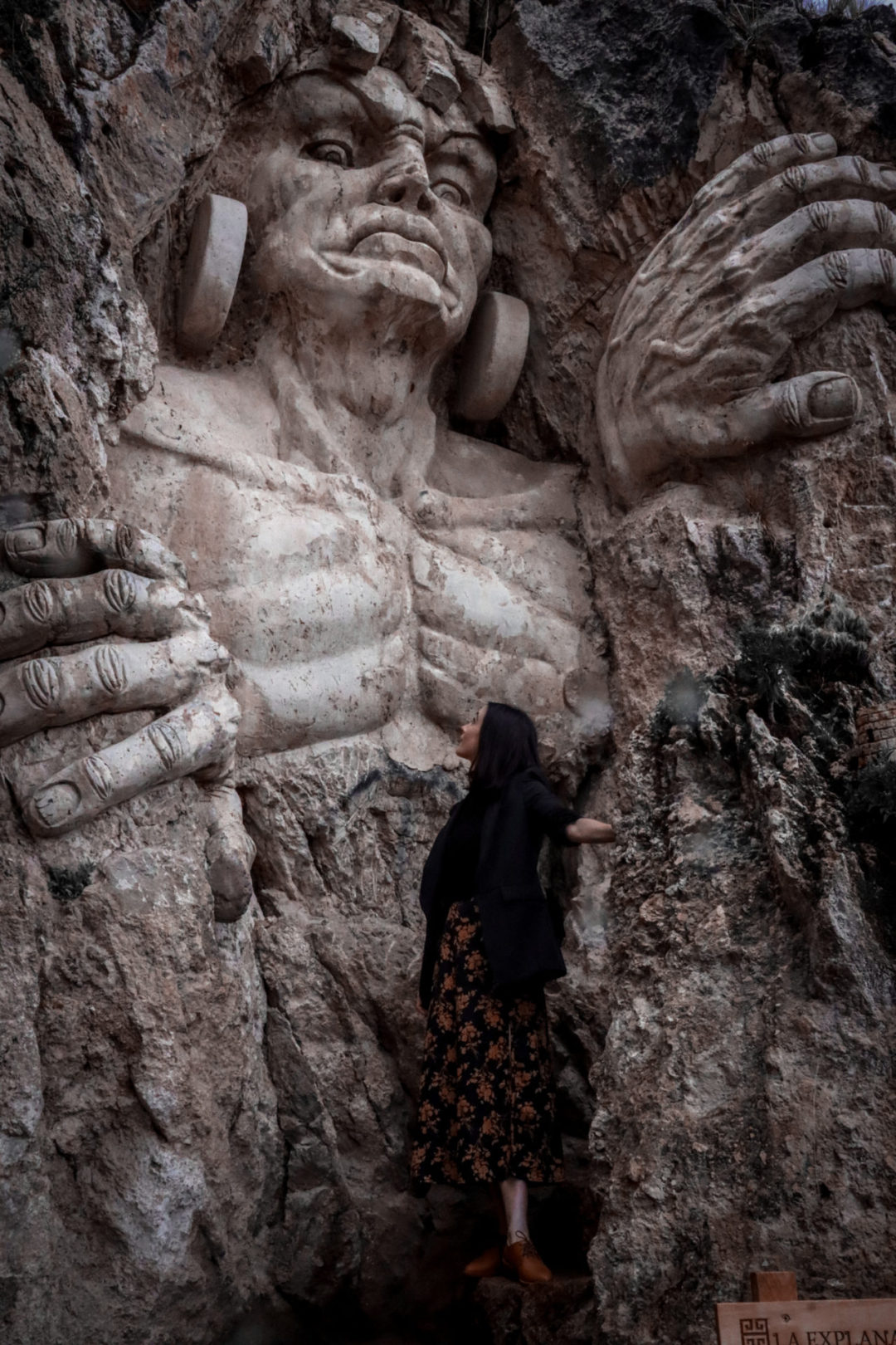 Travel Blogger Jordan Gassner looking up at a sculpture of Tocay Capac, a leader of the pre-Incas, at Apukunaq Tianen near Cusco, Peru