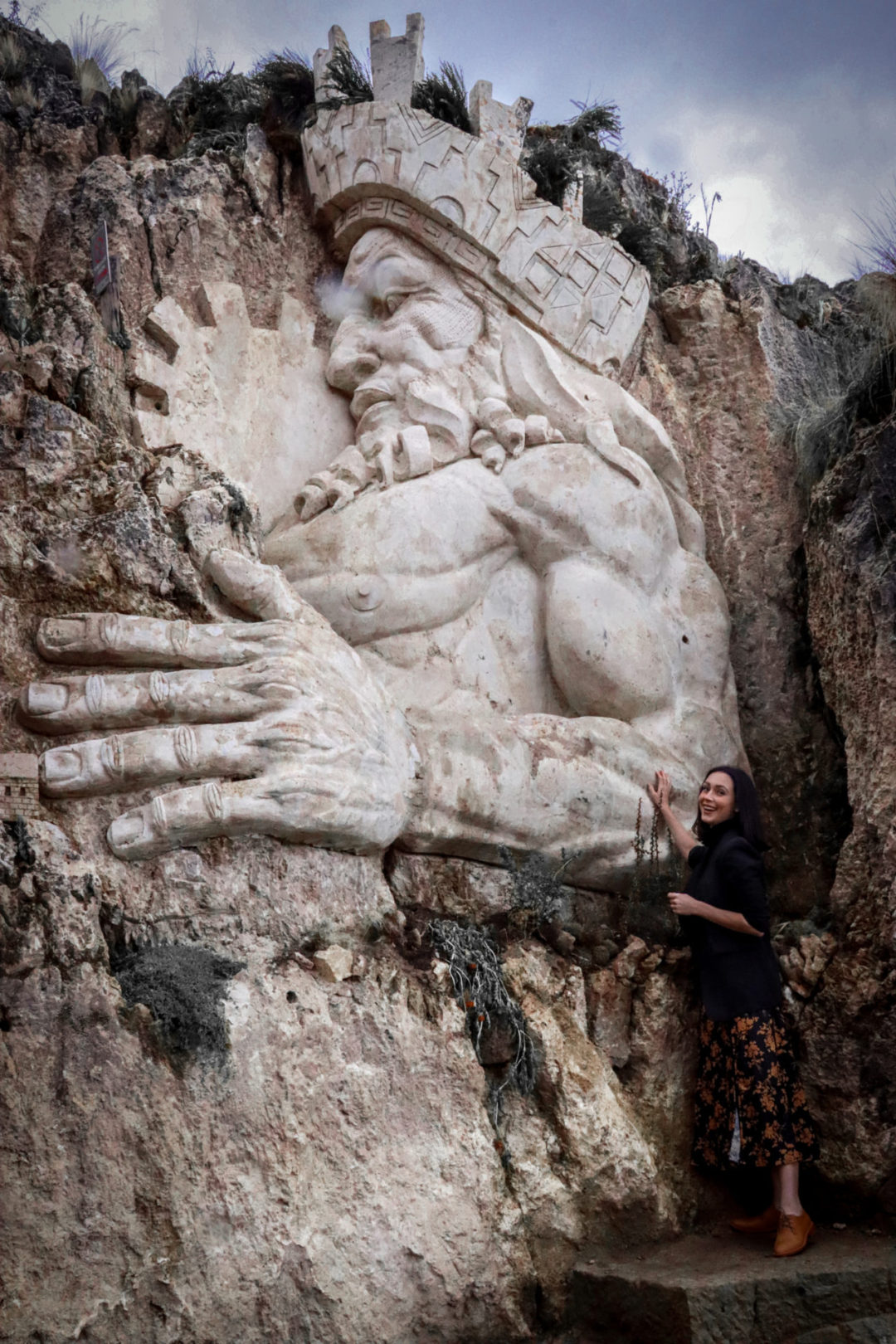 Travel Blogger Jordan Gassner smiling near the base of the large sculpture of Wiracocha at Apukunaq Tianen near Cusco, Peru
