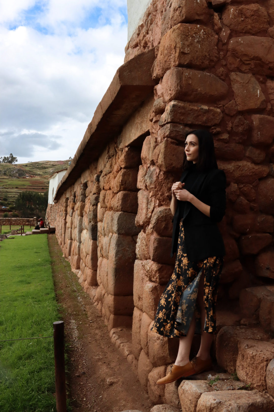 Travel Blogger Jordan Gassner leaning against one of the walls surrounding Antigua Plaza de Chinchero in Peru's Sacred Valley