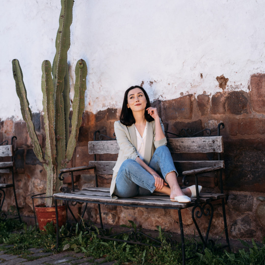 Travel Blogger Jordan Gassner looking off with her feet up on the bench at Calle Tocuyeros in Cusco, Peru