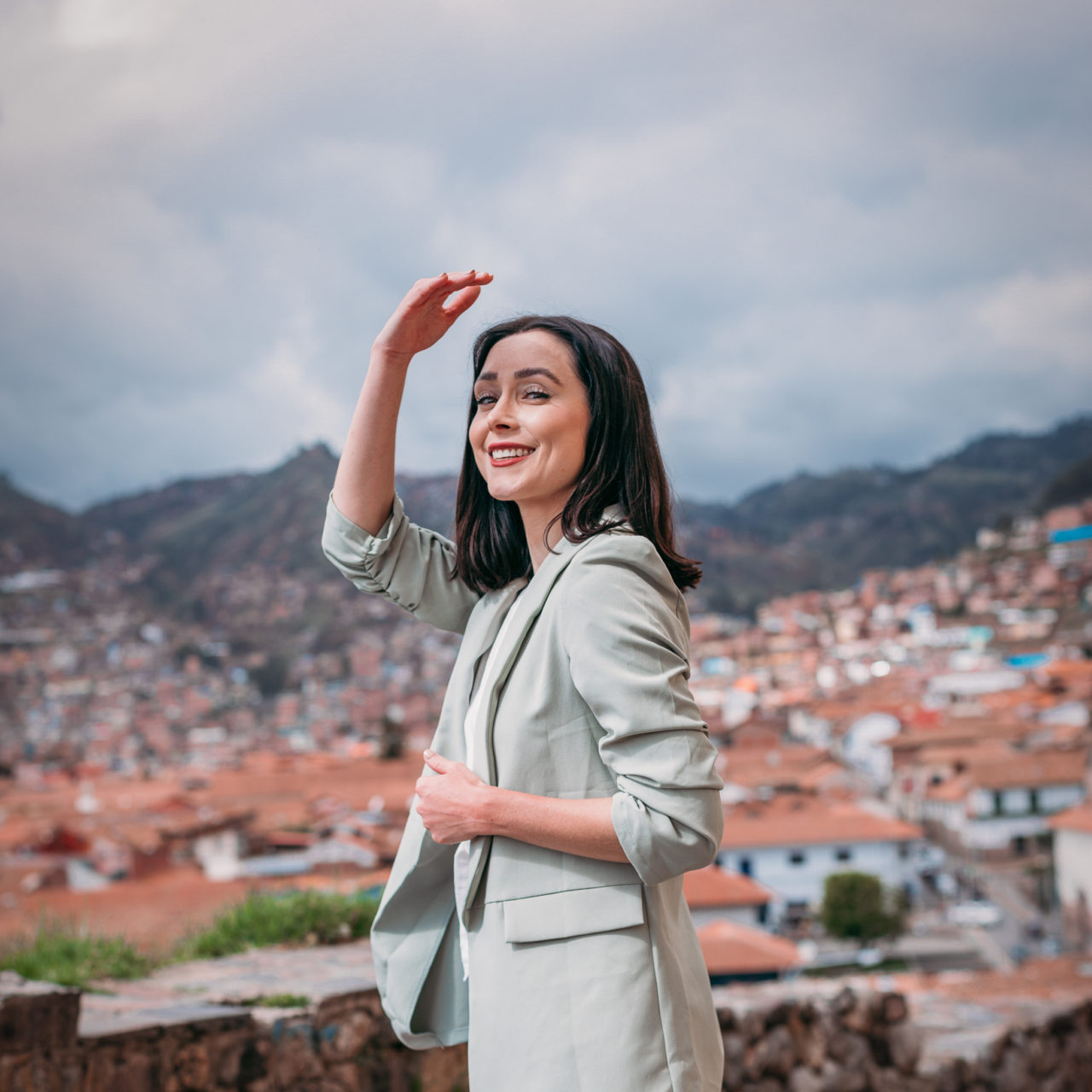 Travel Blogger Jordan Gassner shielding her eyes from the sun on Calle Waynapata overlooking Cusco's Plaza De Armas