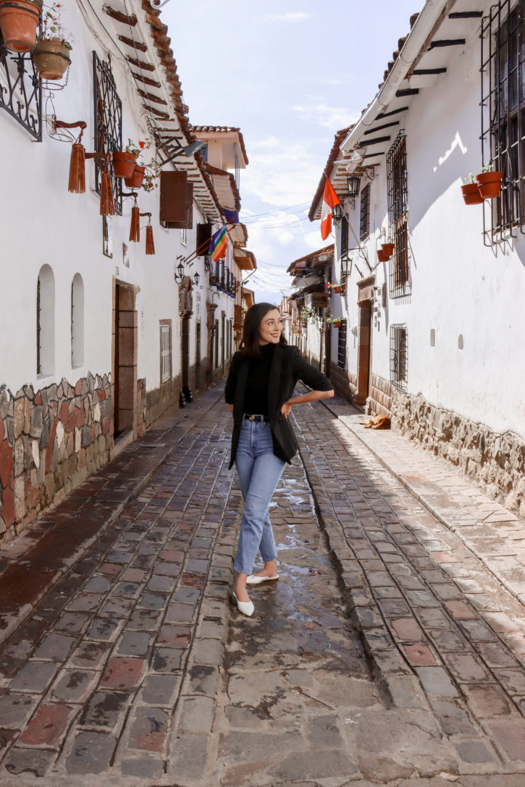 Travel Blogger Jordan Gassner smiling with hands on her hips at Calle Carmen Alto in Cusco, Peru