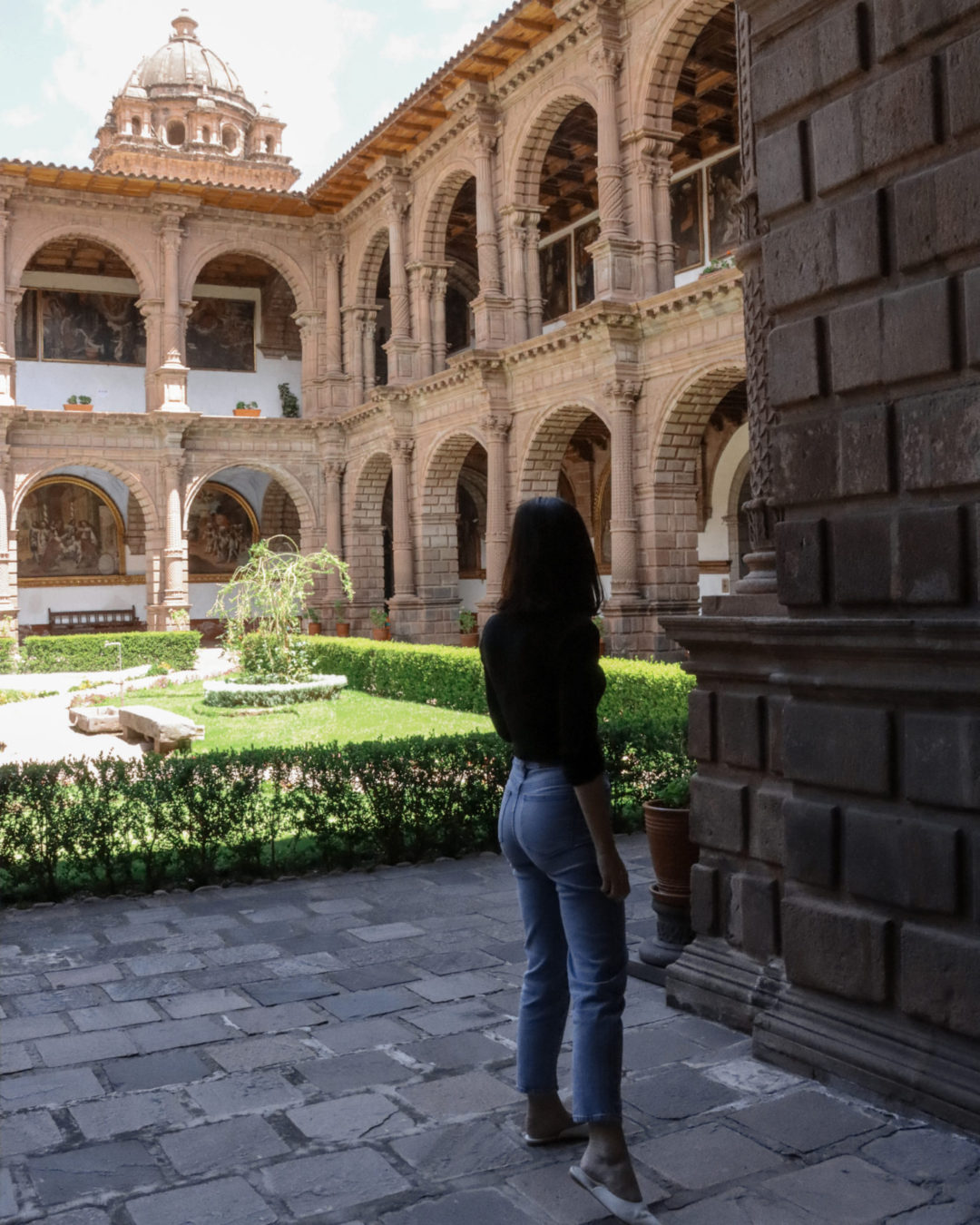Travel Blogger Jordan Gassner standing in the shade and looking out toward the center courtyard in Cusco, Peru