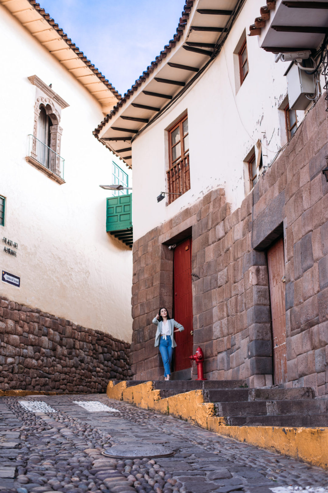 Travel Blogger Jordan Gassner standing in front of a red door and a green balcony on Cusco's Córdoba del Tucumán