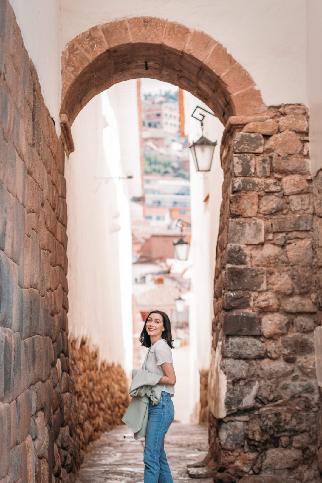 Travel Blogger Jordan Gassner standing and smiling in the archway at Calle Siete Culebras in Cusco, Peru.