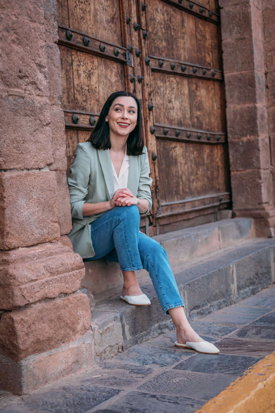 Travel Blogger Jordan Gassner sitting in the doorway at Palacio Nazarenas in Cusco, Peru.