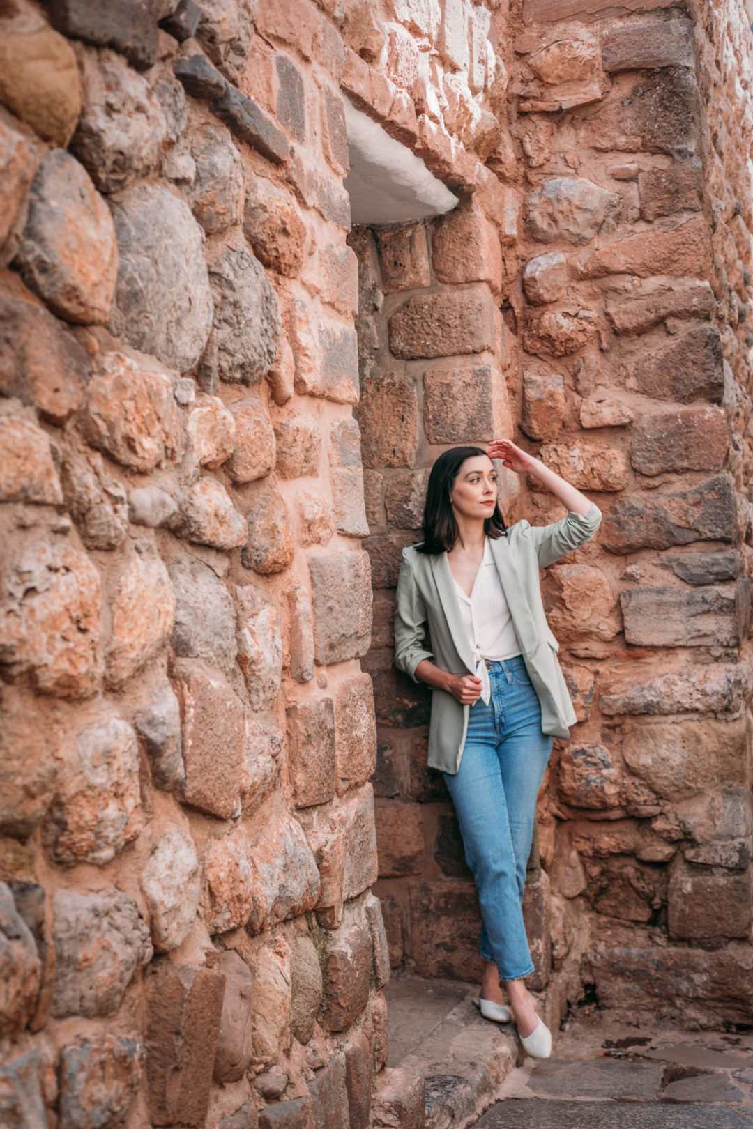Travel Blogger Jordan Gassner peering out of a doorway at Calle Siete Culebras near Plazoleta de las Nazarenas in Cusco, Peru.
