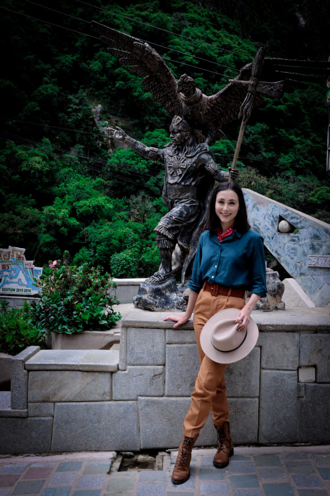 Travel Blogger Jordan Gassner in front of the bronze Statue of the Inca Cosmological Trilogy in Aguas Calientes, Peru