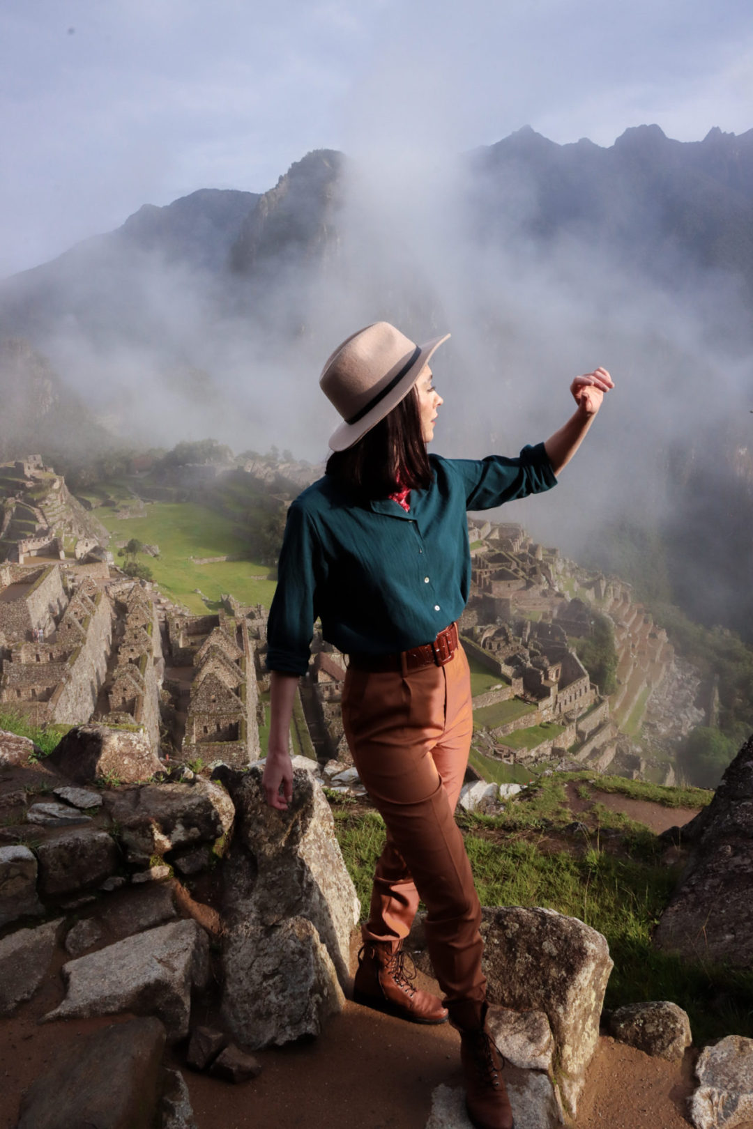 Travel Blogger Jordan Gassner shielding her eyes from the sun on the steps of Machu Picchu's Lower Terrace in Peru