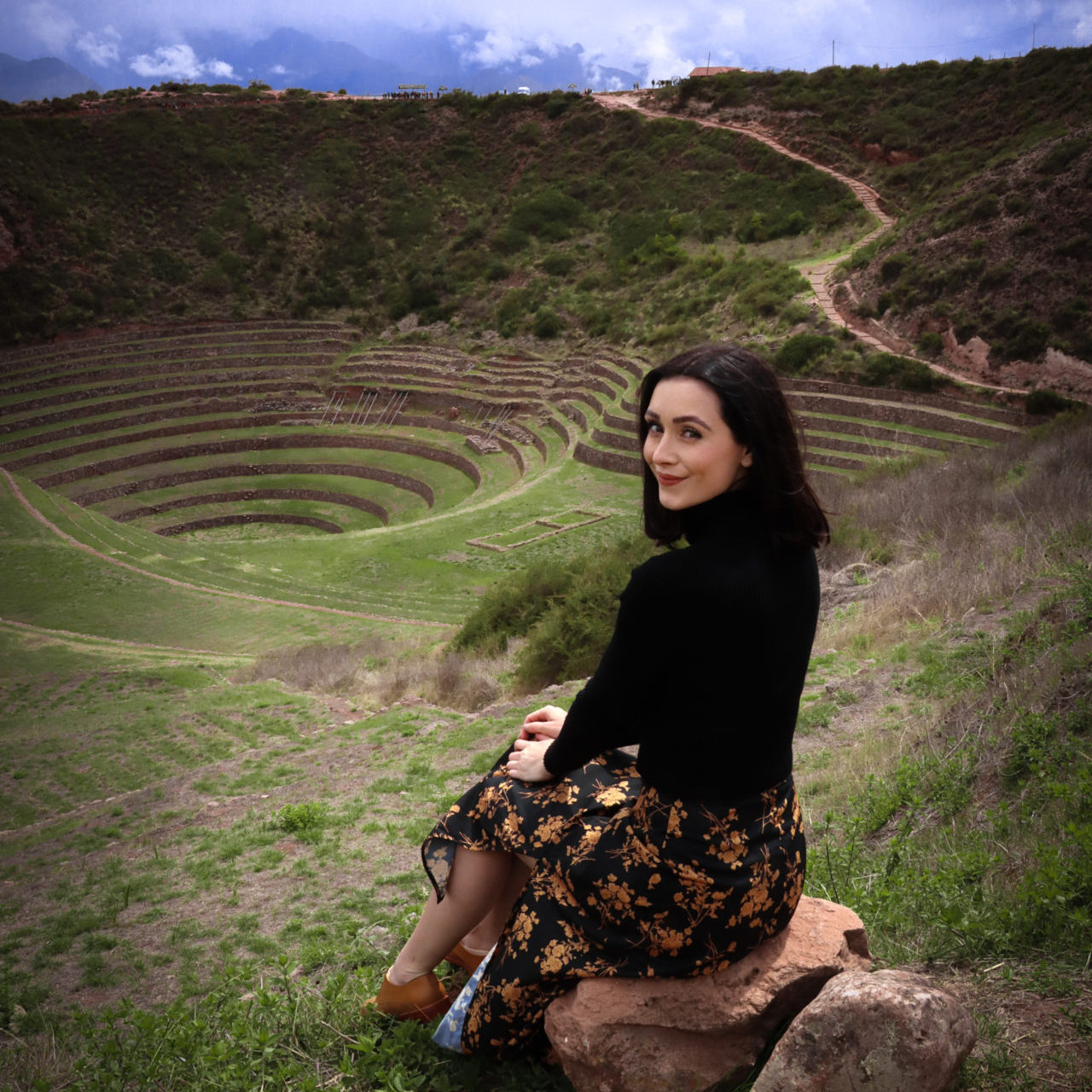 Travel Blogger Jordan Gassner looking back while sitting on a rock at the top of the empty Moray Archaeological Site in Peru