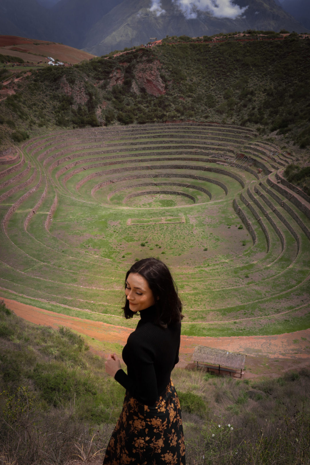 Travel Blogger Jordan Gassner looking down and smiling while standing at the top the Moray Archaeological Site in Peru