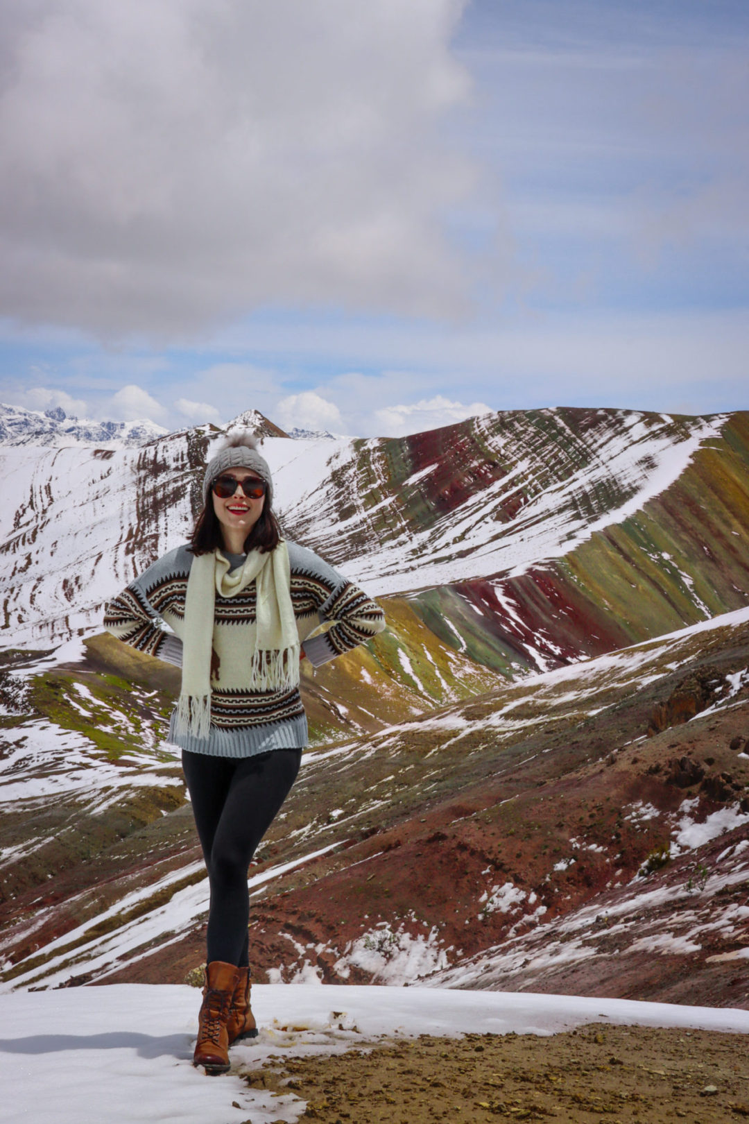 Travel Blogger Jordan Gassner smiling with hands on her hips at the top of the Palccoyo Rainbow Mountain