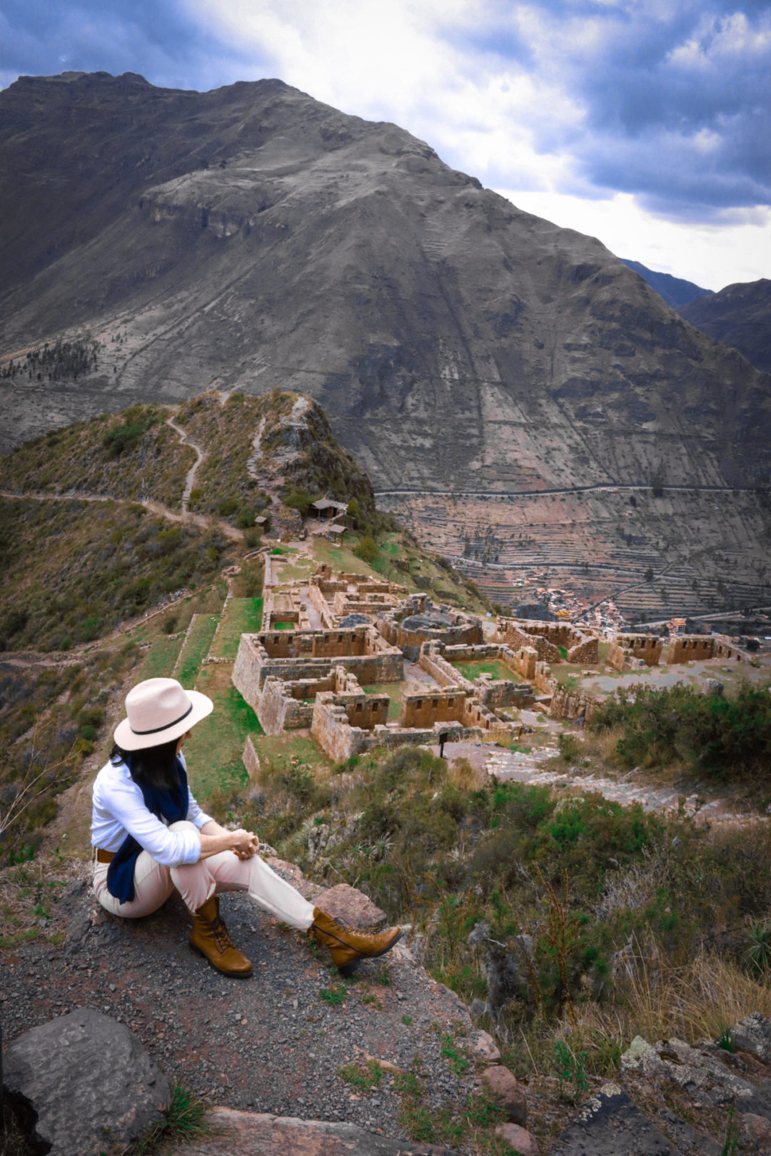 Travel Blogger Jordan Gassner sitting from a view point high above some of the ruins in Pisac, Peru