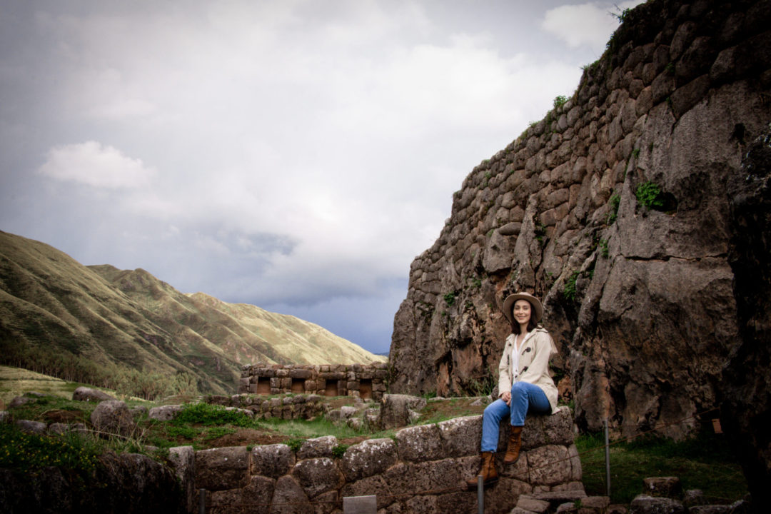Travel Blogger Jordan Gassner sitting atop a terrace at Puca Pucara in Cusco, Peru