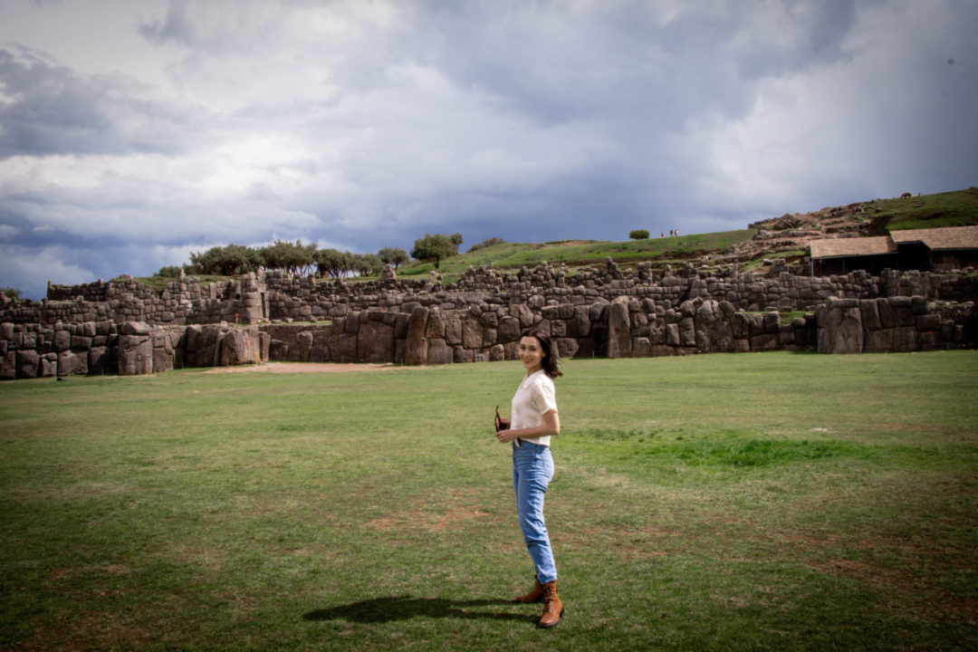 Travel Blogger Jordan Gassner standing on the empty plain in in the middle of the Sacsayhuamán ruins in Cusco, Peru