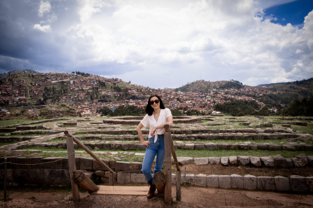 Travel Blogger Jordan Gassner leaning against a set of stairs used by those visiting the ruins of Sacsayhuamán in Cusco, Peru