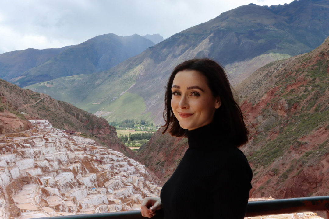 Travel Blogger Jordan Gassner smiling in the shade above Salinas De Maras in The Sacred Valley, Peru