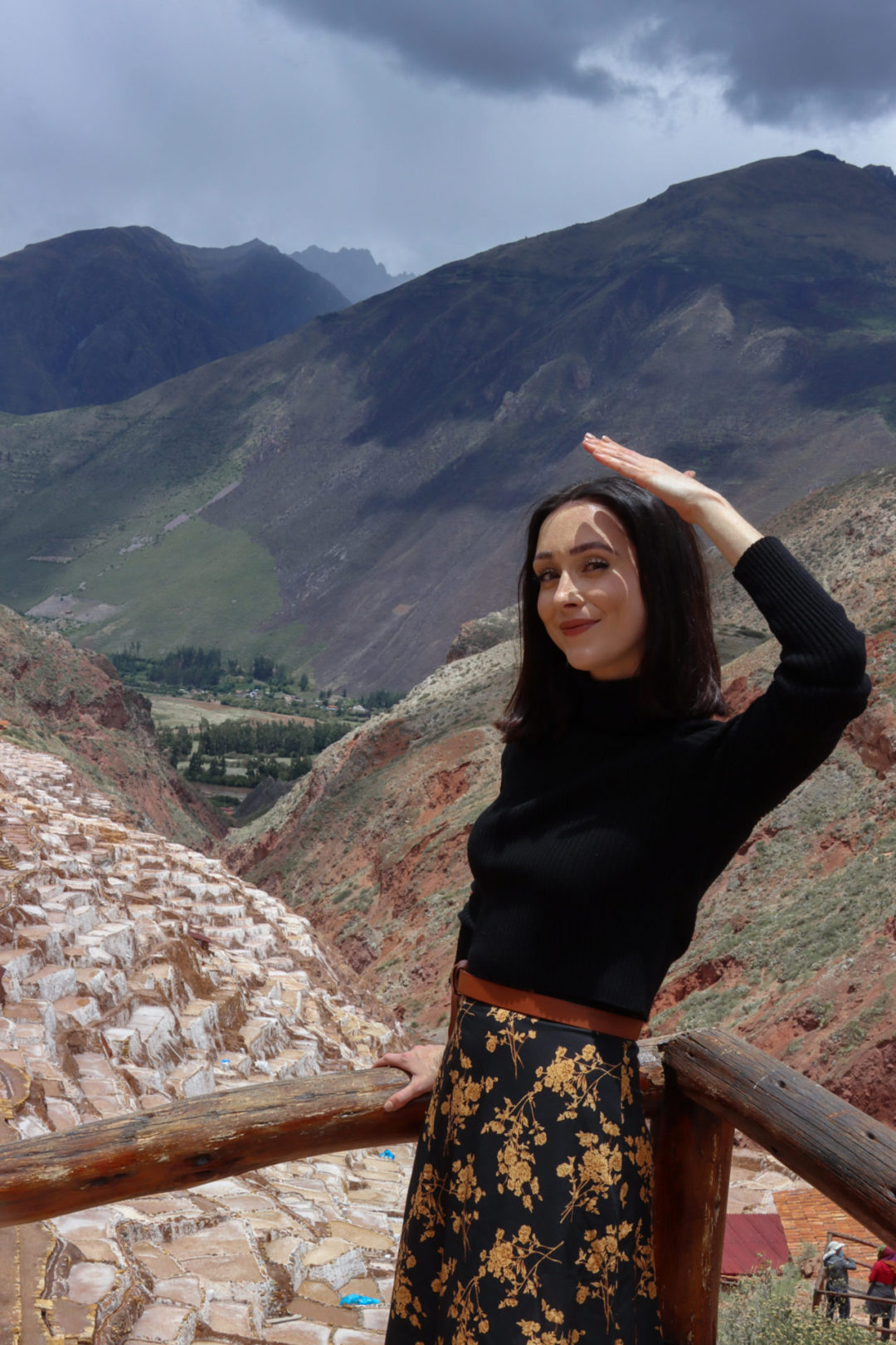 Travel Blogger Jordan Gassner shielding her eyes from the sun while standing at a rail overlooking Salinas De Maras