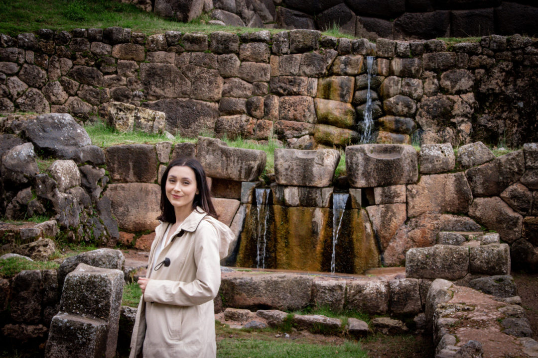 Travel Blogger Jordan Gassner standing and smiling near the Inca ruins of Tambomachay near Cusco, Peru