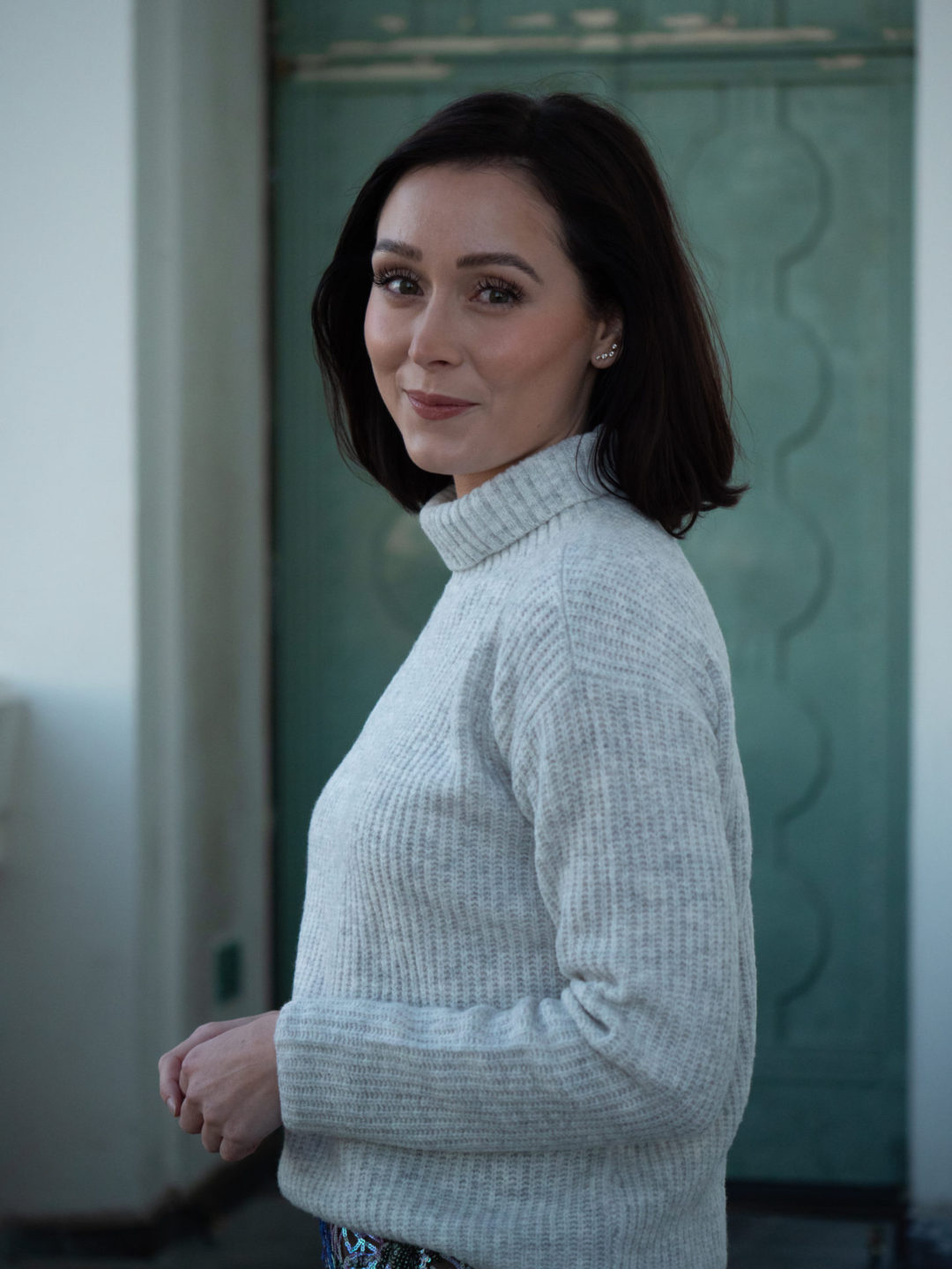 Travel Blogger Jordan Gassner smiling and standing in front of a mint art deco door behind Griffith Observatory in Los Angeles