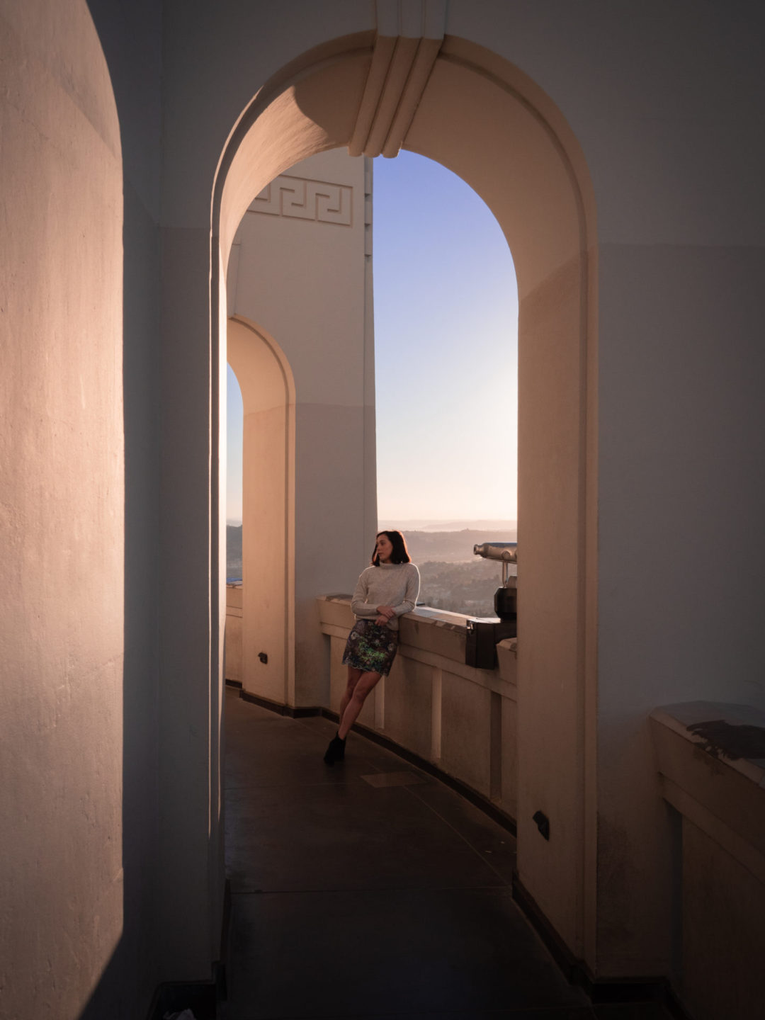 Travel Blogger Jordan Gassner leaning against the interior archway next to a tower viewer on the backside of Griffith Park Observatory