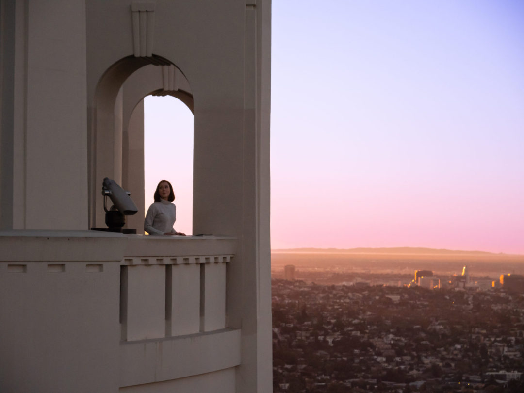 Travel Blogger Jordan Gassner looking up at the Griffith Observatory from its archway at sunset in Los Angeles, California