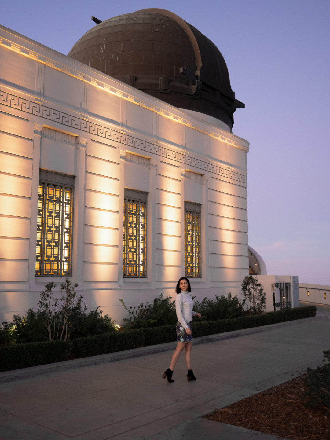 Travel Blogger Jordan Gassner walking in front of the western rotunda at the Los Angeles Griffith Observatory at twilight