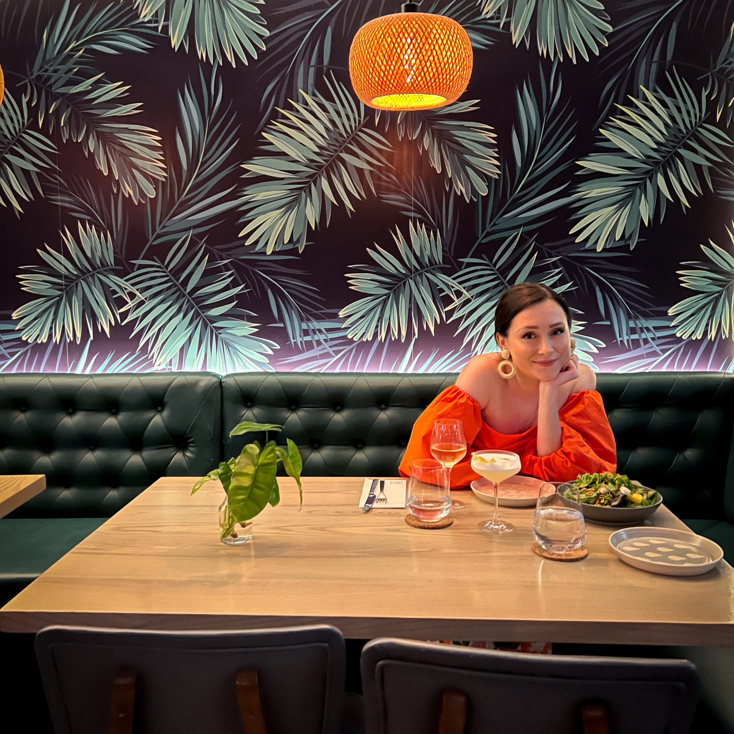 Travel Blogger Jordan Gassner smiling with her head in her hands at a table inside Bayside Restaurant on Grand Cayman Island