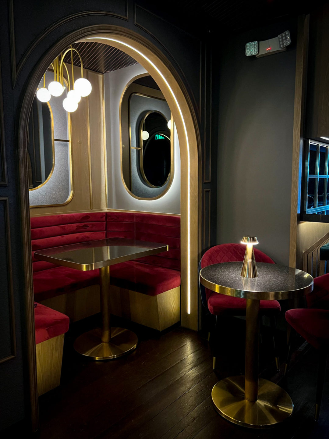 A gold built-in booth with plush red cushions inside Next Door Lounge