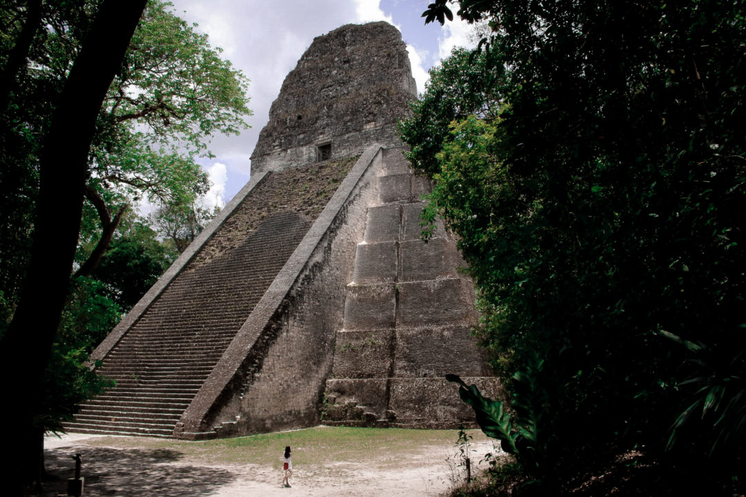 Travel Blogger Jordan Gassner dwarfed by the major Tikal Temple V in Guatemala