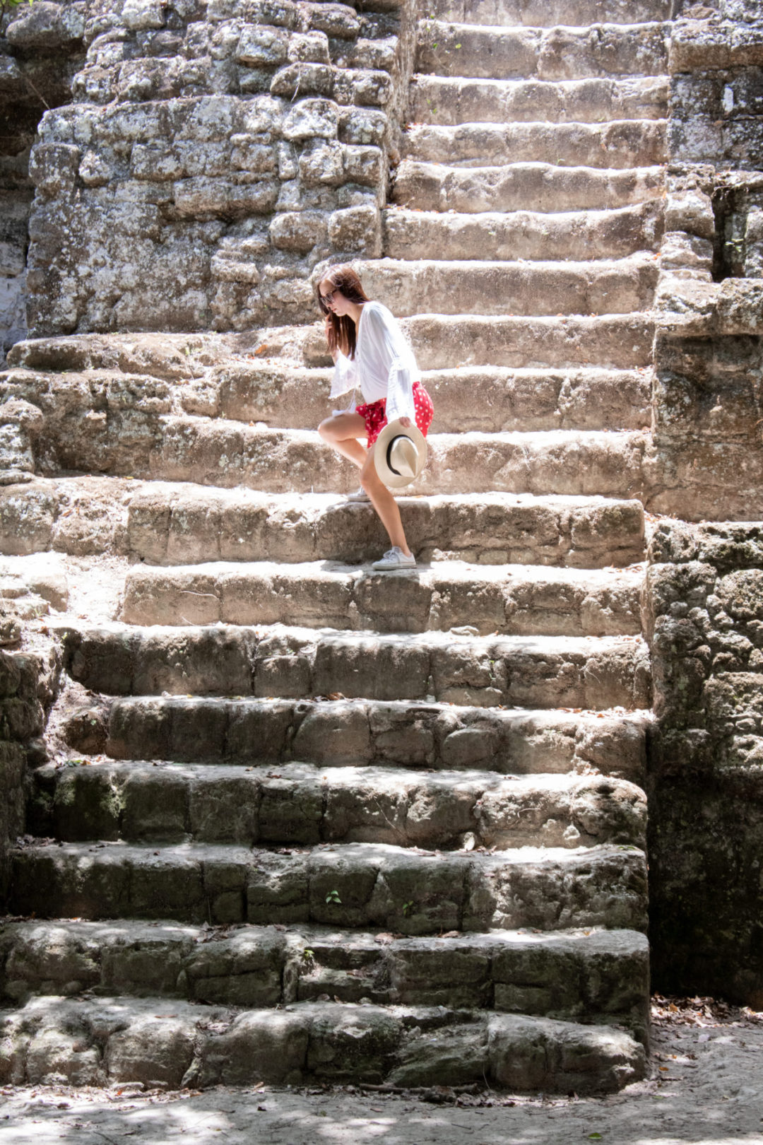 Travel Blogger Jordan Gassner side-stepping down a steep staircase along a Mayan pyramid in Guatemala's Tikal National Park