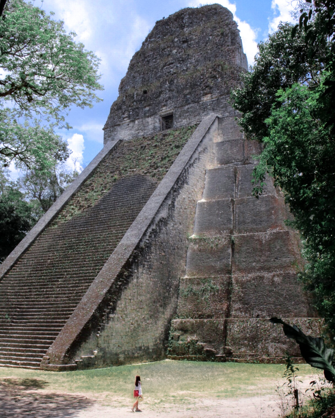 Travel Blogger Jordan Gassner walking in front of the giant Tikal Temple V in Guatemala