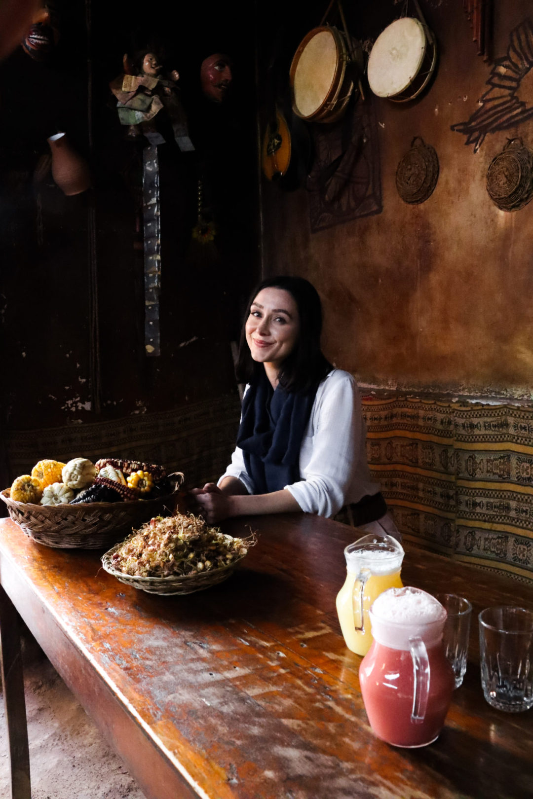Travel Blogger Jordan Gassner sitting at a table with a pitcher of chicha and a pitcher of chicha moradabar in Peru's Sacred Valley