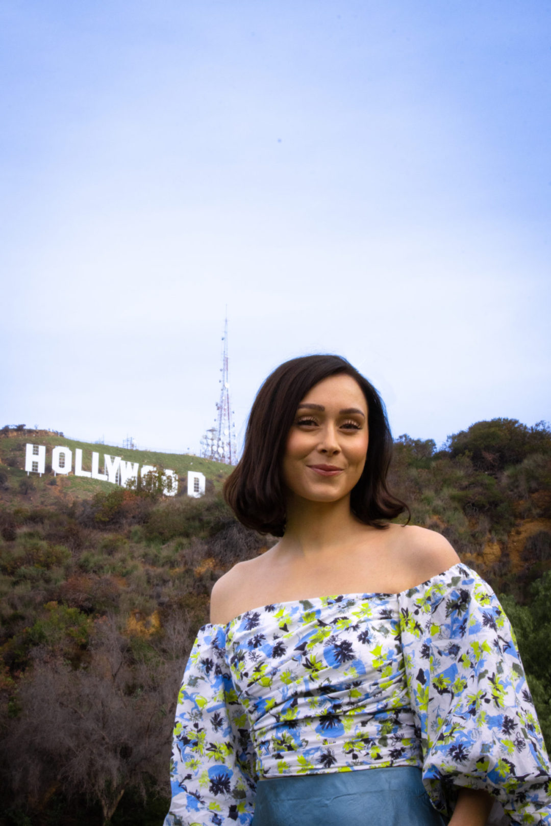 Travel Blogger Jordan Gassner smiling at camera in front of a view of the Hollywood Sign at Lake Hollywood Park