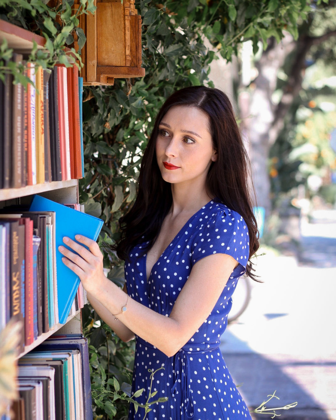 Travel Blogger Jordan Gassner looking through a colorful bookshelf at Bart's Books in Ojai, California