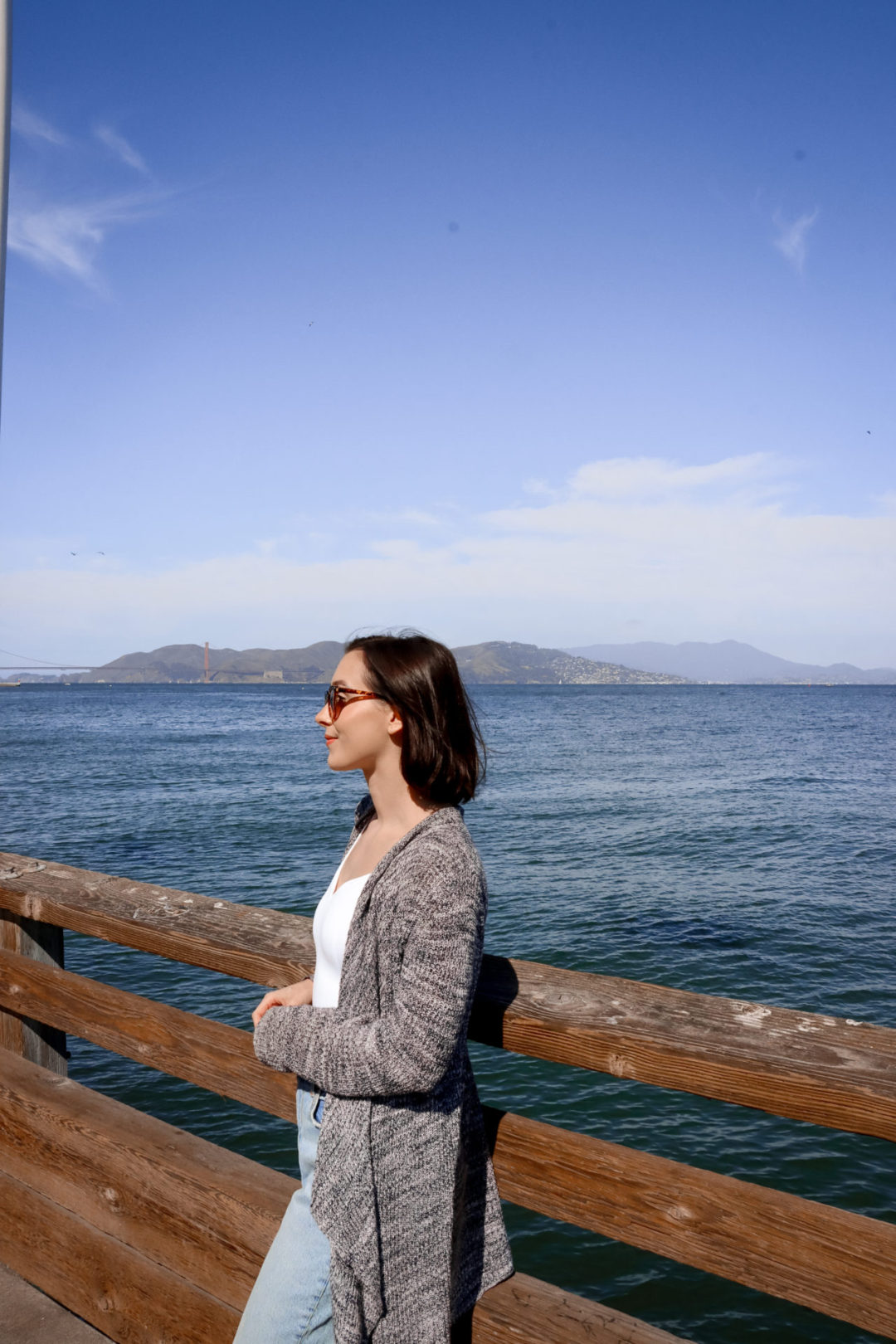 Travel Blogger Jordan Gassner smiling in front of the Fog Harbor Fish House on the second floor walkway at Pier 39 in San Francisco