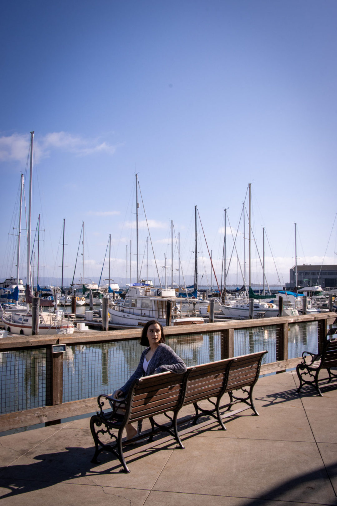 Travel Blogger Jordan Gassner sitting and looking back on a bench overlooking the marina at Pier 39 in San Francisco