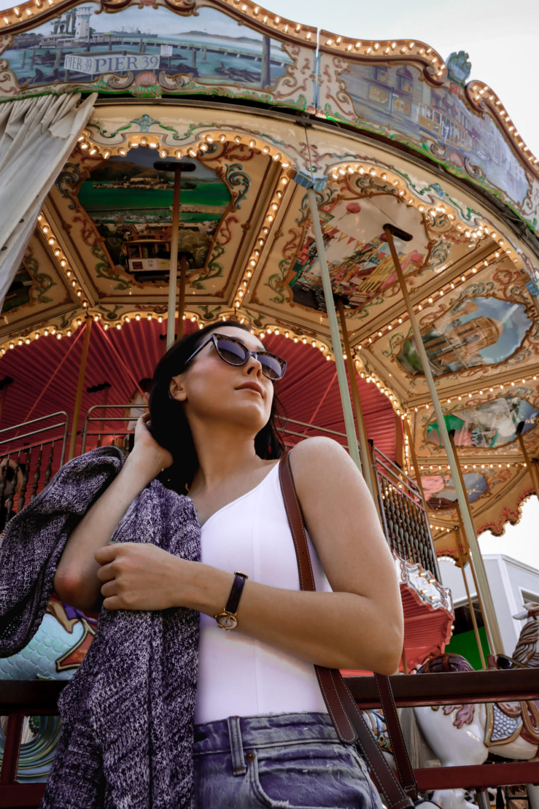 Travel Blogger Jordan Gassner fixing her hair in front of the carousel at Pier 39 in San Francisco