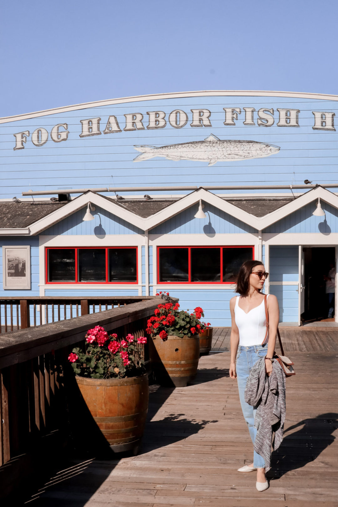 Travel Blogger Jordan Gassner standing in front of the Fog Harbor Fish House on the second floor walkway at Pier 39 in San Francisco