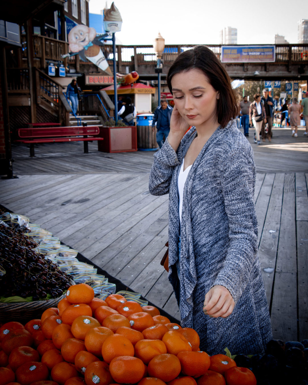 Travel Blogger Jordan Gassner reaching for an orange at a fruit stand in San Francisco Pier 39