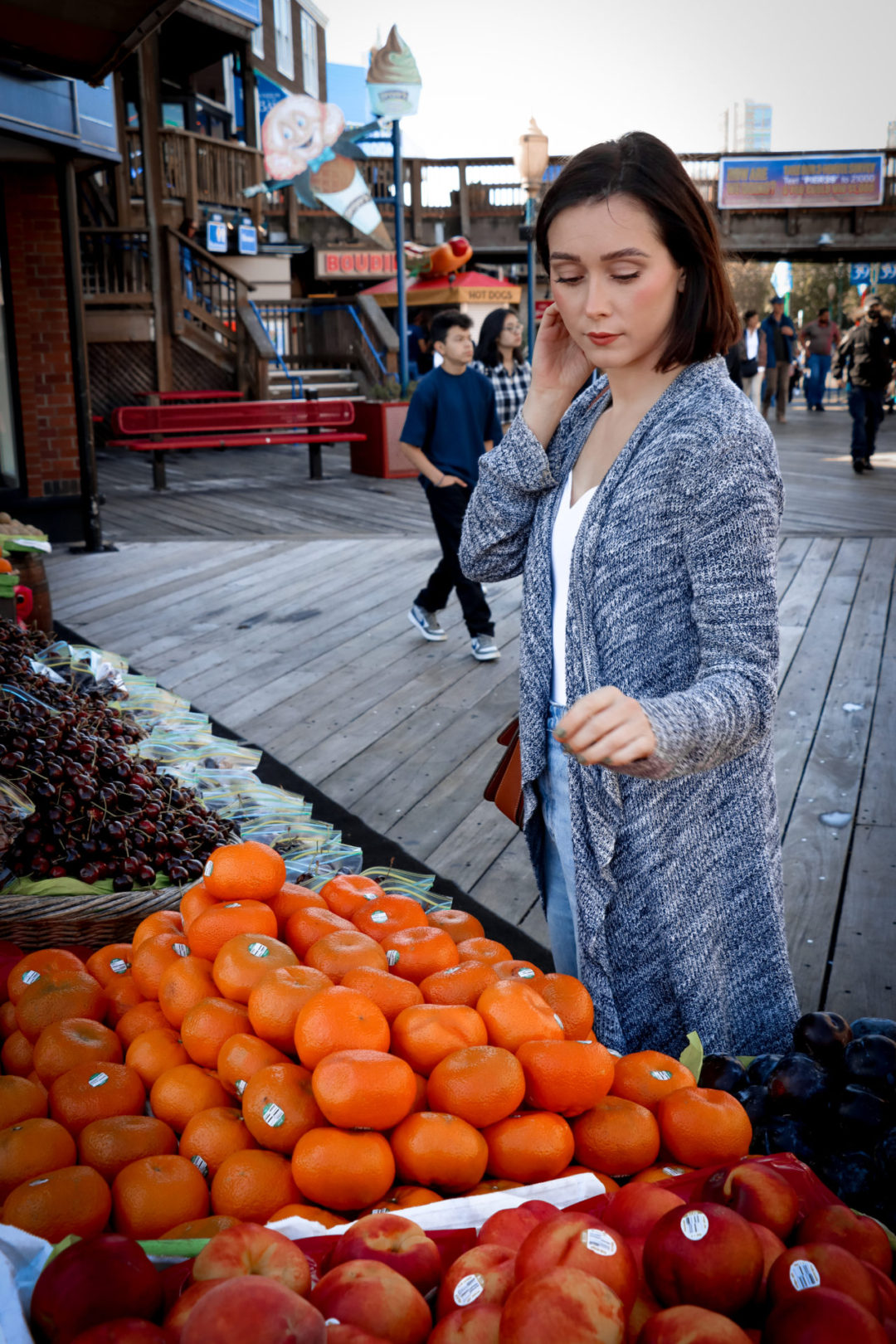 Travel Blogger Jordan Gassner deciding on which orange to grab from a fruit stand in San Francisco Pier 39