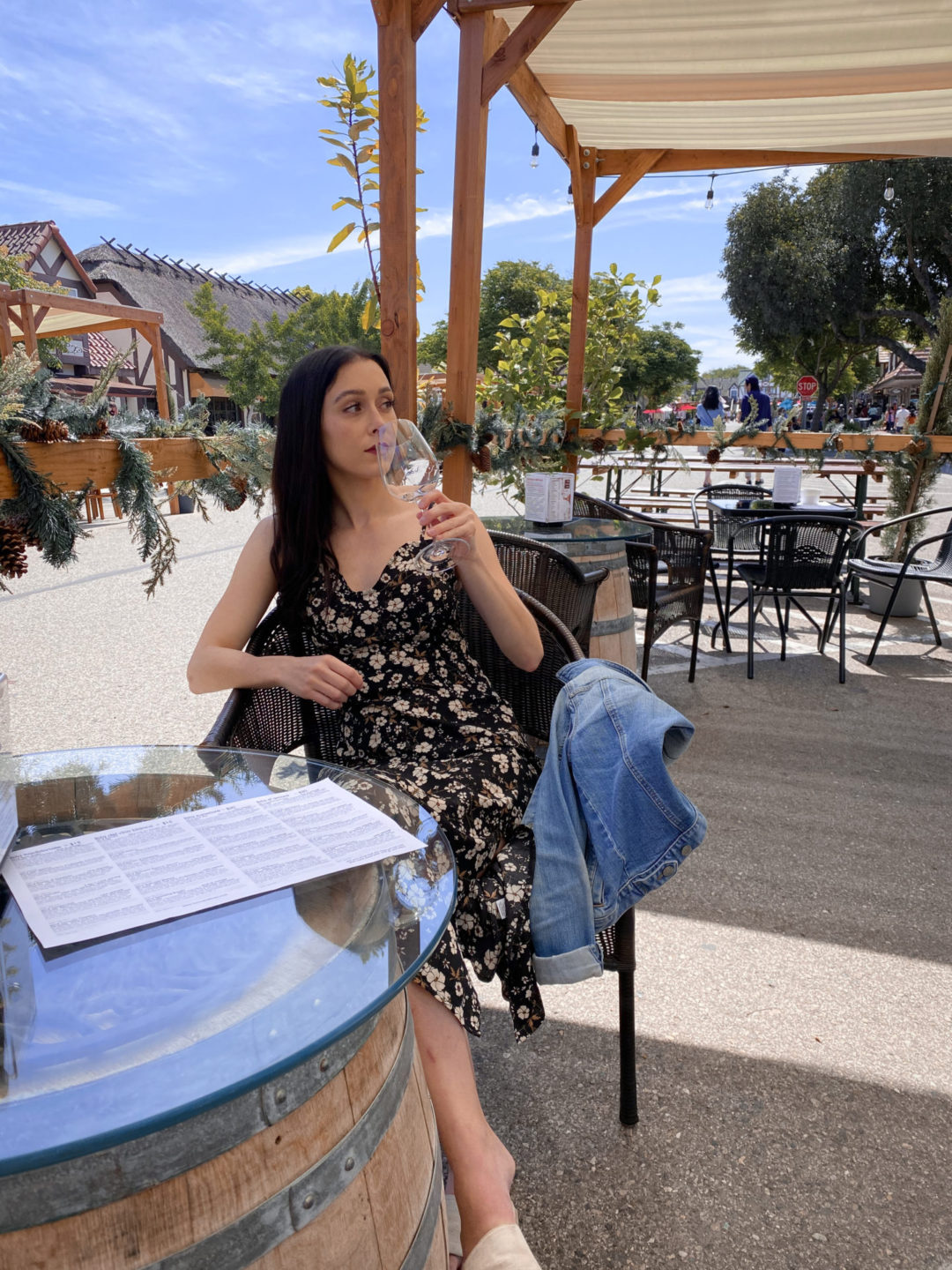 Travel Blogger Jordan Gassner drinking a glass of white wine at a "beer garden" style seating area at one of Solvang's many tasting rooms