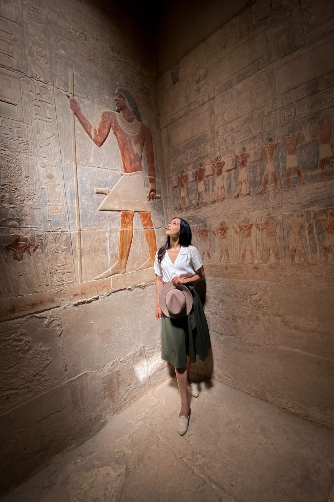 Travel Blogger Jordan Gassner staring up at the faded paint colors of the hieroglyphics inside Mehou's Masataba in Egypt