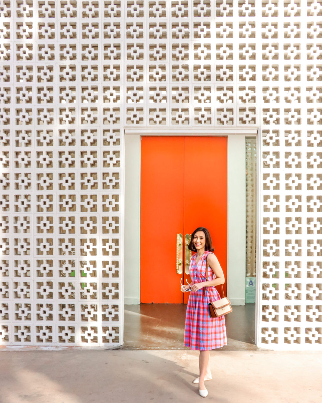 Travel Blogger Jordan Gassner standing in front of the orange double doors at the Parker Palm Springs in California
